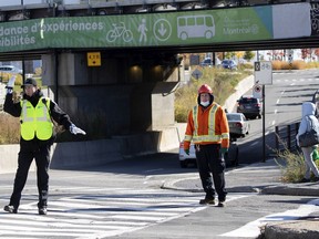 An SPVM cadet directs traffic as a city worker checks on a new lighting configuration at the corner of de Maisonneuve and Décarie Blvds. in N.D.D. on Sunday, Oct. 25, 2020.