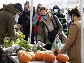 People line up for locally grown vegetables during the last session of the season at Marché Ste-Anne in Ste-Anne-de-Bellevue, on Saturday, Oct. 24, 2020.