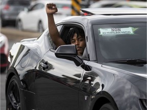 A man shows his support for the BLM movement during a "Driving while Black" convoy and gathering that criss crossed Montreal, on Sunday, July 5, 2020.