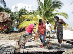 Volunteers clean debris from Hurricane Delta in 'Playa Tortuga' on Oct. 8, 2020, in Cancun, Mexico. Hurricane Delta made landfall in the Mexican east coast in the morning of Oct. 7, between Cancún and Playa del Carmen, forcing evacuations in touristic areas.