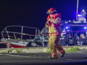 A firefighter in a life jacket walks away from a rescue boat at the pier at 34th ave. and St-Joseph Blvd. in Lachine after a car was submerged Oct. 6, 2020.