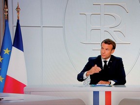 This picture shows a screen displaying French President Emmanuel Macron as he addresses the nation during a televised interview from the Elysee Palace concerning the situation of the novel coronavirus Covid-19 in France, in Paris on October 14, 2020. - Macron orders 9:00 pm-6:00 am curfew for Paris, eight other French cities. The French government said on Wednesday it was re-imposing a state of health emergency to contain the spread of Covid-19.