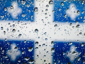 The Quebec flag is seen through water drops on a window in Montreal.