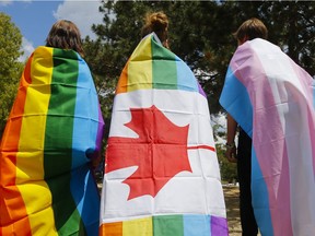 People wear flags supporting the LGBTQ+ communities.