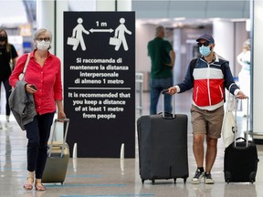 Passengers wearing protective face masks walk at Fiumicino Airport  in Rome, Italy, June 30, 2020.