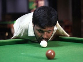 Muhammad Ikram, 32, who was born without arms, plays snooker with his chin at a local club in Samundri, Pakistan, on Oct. 20, 2020.