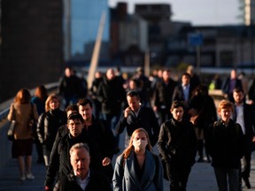 Commuters walk over London Bridge toward the City of London during the morning rush hour on October 15, 2020.