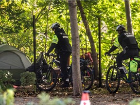 Montreal police on bicycles investigate the tent of some homeless living in a woodland at Souvenir Street in Montreal on Thursday October 8, 2020.