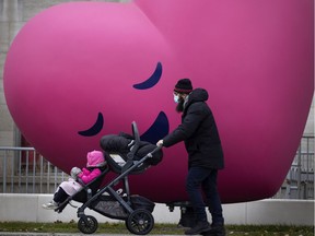 A man wearing a face mask to protect against COVID-19 walks past La Memoire du Coeur at Ste-Justine Hospital in Montreal on Tuesday. The pandemic has forced governments and scientists to learn how to communicate science to the public, a process that must continue, experts say.