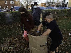 Emilio Musacchio watches as his children, Emma and Luca, gather leaves at the St. John Brébeuf Parish in LaSalle.