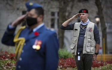 Veteran John Malevich, right, who served in the Canadian military in Bosnia and Afghanistan, salutes during scaled-down Remembrance Day ceremony at the Cenotaph in Montreal's Place du Canada in 2020.