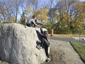Thomas D'Aoust helps his sister Sarah D'Aoust to climb a boulder at a new playground, Prairie Park, in Beaconsfield on Sunday