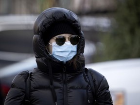 Bundled up for all conditions, sun, cold and COVID-19, a shopper walks through the outdoor kiosks at the Atwater Market on Nov. 21, 2020.