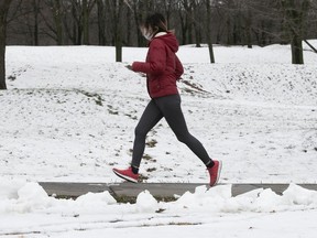 A woman runs on Park Ave. near Mount Royal on Monday, November 23, 2020 following overnight snowfall.