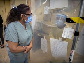 Annie Boto, left, head nurse in the hot zone, speaks with a co-worker through heavy plastic separating the nursing station from the halls at the Donald Berman Maimonides Geriatric Centre in Côte-St-Luc on Tuesday, November 24, 2020.