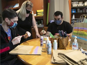 Coordinator at Light a Dream store, Lynn MacDonald (centre), gets a close look at the work of Geremy To (right) and Hagop Shahbazian on Saturday during the COVID-19 pandemic.