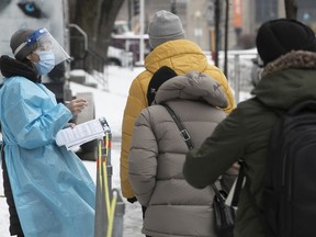 A health-care worker goes through questions to people waiting in line for COVID-19 testing at the Park Extension COVID-19 clinic on Nov. 26, 2020.