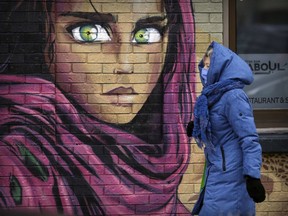 A masked pedestrian passes the mural on the wall of the Fenêtre sur Kaboul restaurant in Montreal on Thursday, November 26, 2020.