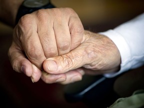 A 92-year-old man holds the hand of his care-giver: "There's nothing we can do about the moments that we have lost, but let's make the most of the time we have with those we love, in whatever way we can," Fariha Naqvi-Mohamed writes.