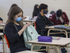 A masked student unpacks her backpack during French class at John F. Kennedy High School in Montreal last year.