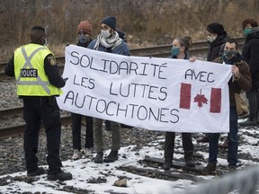 A Canadian Pacific police officer talks with people as they block a rail line in Montreal on Friday.