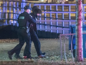 Police officers detain a man in an area where multiple people were stabbed near the Parliament Hill area of Quebec City on Sunday.