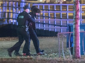 Police officers detain a man in an area where multiple people were stabbed in Quebec City on Sunday. Two of the victims died, while five were injured.