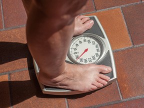 Overweight person weighing herself on a bathroom scale.