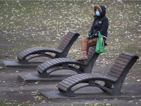 A woman wears a face mask as she sits in a park in Montreal, Sunday, Nov. 15, 2020.