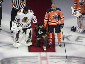 Minnesota Wild's Matt Dumba takes a knee during the national anthem flanked by Edmonton Oilers' Darnell Nurse, right, and Chicago Blackhawks' Malcolm Subban before an NHL playoff game in Edmonton, Saturday, Aug. 1, 2020.
