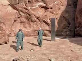 Utah public officials walk around a random metal monolith, mysteriously planted in the remote desert.
