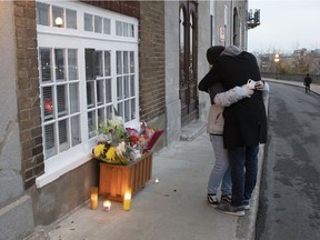 Dimitry Montigny embraces Jessica Peloquin, left, after laying flowers in front of Suzanne Clermont's house in Quebec City Nov. 1, 2020. Clermont was one of two people killed Saturday night by a man wielding a sword. Peloquin, who took the 911 call, was in tears.