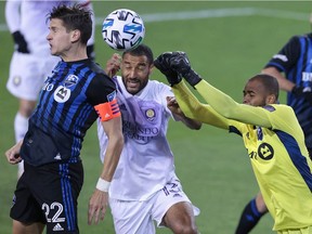Orlando City goalkeeper Pedro Gallese (1) punches the ball away from Montreal Impact defender Jukka Raitala (22) as forward Tesho Akindele (13) defends during the first half at Red Bull Arena in Harrison, N.J., on Sunday, Nov. 2, 2020.