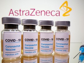 Vials with a sticker reading "COVID-19 / Coronavirus vaccine / Injection only" and a medical syringe are seen in front of AstraZeneca logo in this illustration.