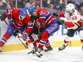 Canadiens Artturi Lehkonen, left, and Nick Suzuki battle for the puck with Calgary Flames Travis Hamonic, rear, and Oliver Kylington in January. Under the NHL's plan for the 2021 season, all seven Canadian teams would play in the same division.