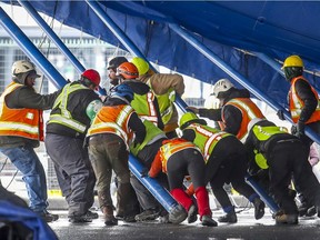 Workers push poles into place to raise the Big Top at Jacques-Cartier Pier in preparation for the Cirque du Soleil's newest production Under the Same Sky in Montreal on March 4, 2020.