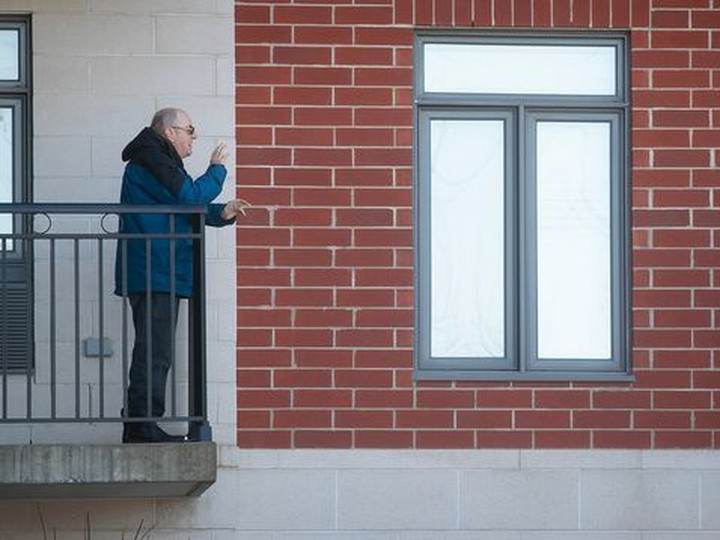  During the first wave of COVID-19 in March, these two neighbours at a Blainville retirement home share a conversation from their balconies. The red brick wall emphasizes the social distance between them.