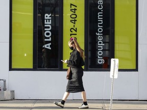 A masked woman walks by a closed retail store on Ste-Catherine St. in Montreal Nov. 9, 2020.