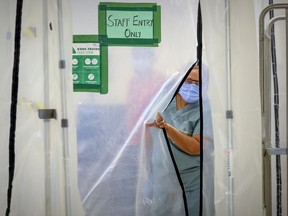 Annie Boto, head nurse in the hot zone, slips through a plastic wall separating the closed-off area at Maimonides Geriatric Centre in Cote-St-Luc Tuesday November 24, 2020. Differing perceptions of this photo illustrate the great divide, Lawrence Rudski writes.