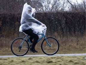 A cyclist not only covers his face for COVID-19 protection, but covers most of his body with a plastic bag as he rides along the bike path in Verdun during rainfall on Tuesday, December 1, 2020.