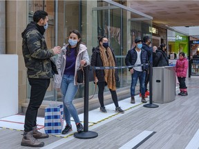 Shoppers line up outside Fairview Mall stores in Pointe-Claire on Saturday, Dec. 5, 2020, because of limitations on store capacity.
