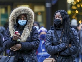 Masked pedestrians walk on Sainte-Catherine St. in Montreal Dec. 11, 2020.