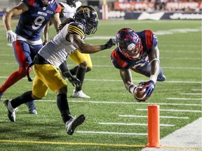 Montreal Alouettes William Stanback dives for the endzone for a touchdown past Hamilton Tiger-Cats Rico Murray  during Canadian Football League game in Montreal Thursday July 4, 2019.