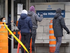 A security guard guides three men to the new entrance after a change in configuration at the Hotel Dieu Covid-19 testing site, in Montreal, on Thursday, December 17, 2020. (Allen McInnis / MONTREAL GAZETTE) ORG XMIT: 65513