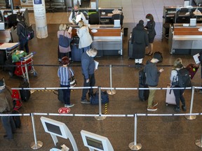 Travellers line up to check in for flights to the United States at Pierre Elliott Trudeau International Airport in Montreal on Friday, December 18, 2020.