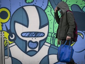 A masked man walks past a mural on Lanaudiere Ave. in Montreal Dec. 21, 2020.