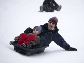 Afshin tries to steer his toboggan away from the wall as he and his son, Jivar enjoy the mild day in King George Park in Montreal, on Monday, December 28, 2020.