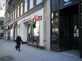 A woman walks along Ste-Catherine St. past closed stores during early afternoon on Tuesday December 29, 2020 during the COVID-19 pandemic. Most of the province is under lockdown including all stores that do not offer essential goods.