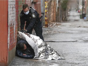 "I was driving around the Plateau on this Monday in April 2020 when I came upon a scene where Montreal police were dealing with a homeless woman sleeping in a lane off Rachel St.," photographer John Mahoney says. "While the police waited for an ambulance, one of them came over with a thermal blanket and covered the woman for warmth against the damp."