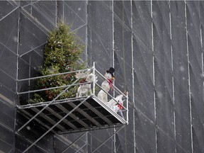 It is beginning to look a lot like Christmas, as snow falls and construction crews decorate the scaffolding on the face of the Customs House, in Montreal on Wednesday, December 2, 2020.